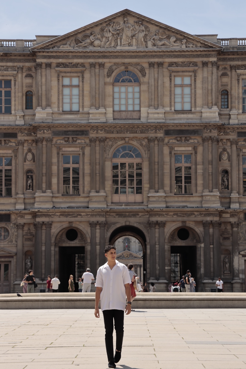 Retrato de un joven caminando frente al Museo del Louvre en París